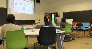 Two men standing in from of projection screen giving a presentation in front of audience