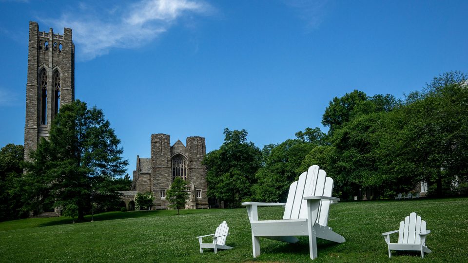 A view of Clothier Hall across Parrish Beach with three Adirondack chairs visible, one of them being the "Big Chair" built by Jake Beckman '04