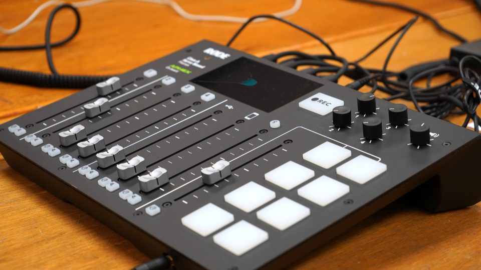 An audio mixer, with an array of sliding knobs and buttons.