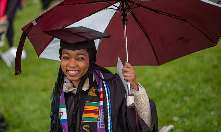 Swarthmore Graduate in cap and gown at commencement holding an umbrella