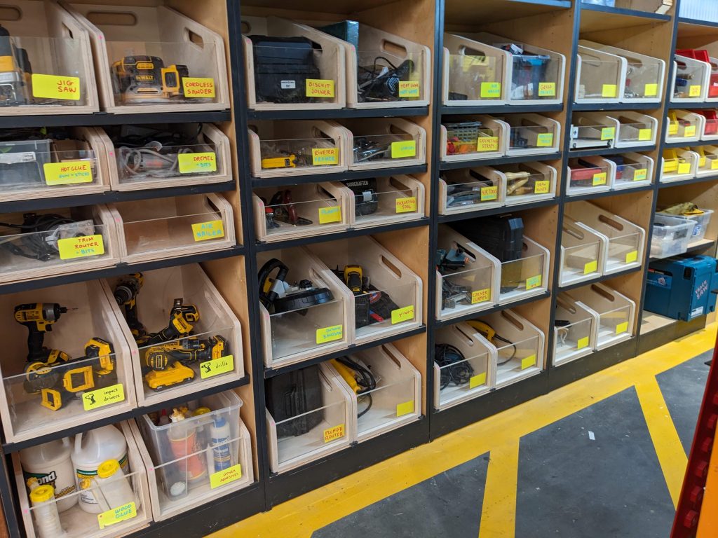 a large storage wall of organized bins in a grid holding tools