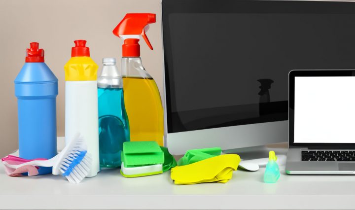 Cleaning supplies next to a desktop and laptop computer