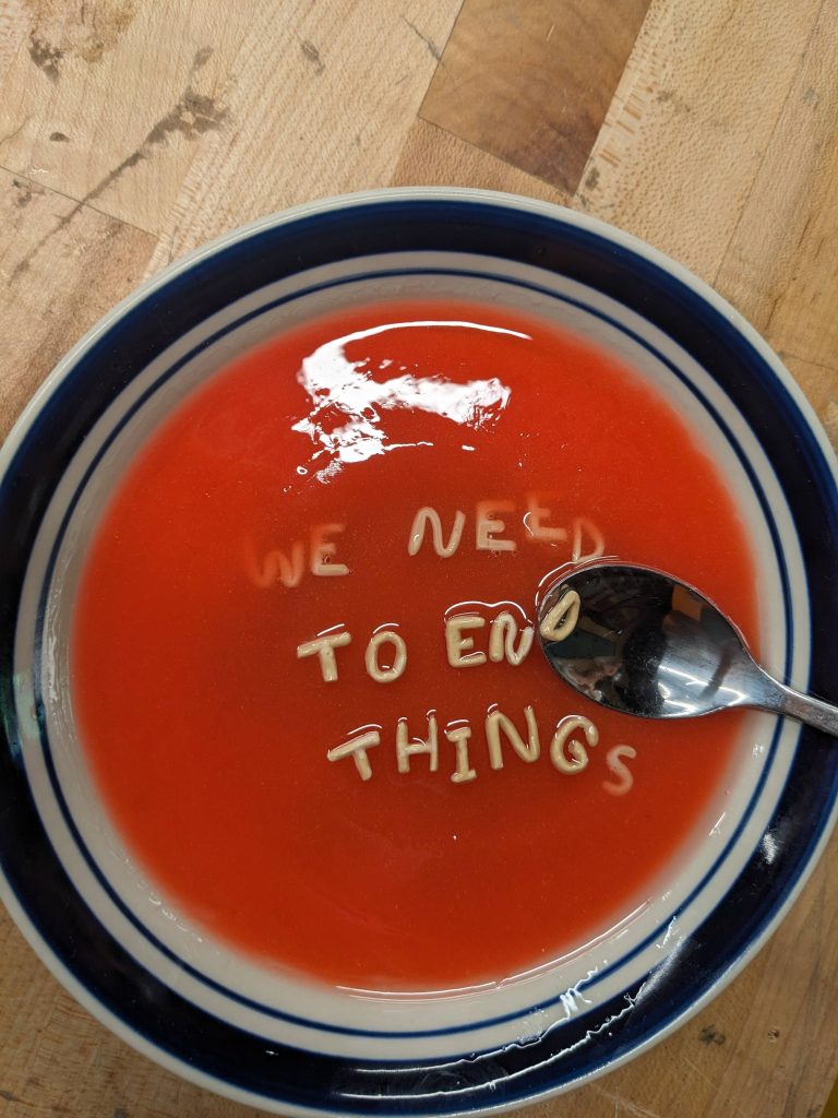 a realistic sculpture of a bowl of tomato alphabet soup with the letters spelling out "we need to end things"