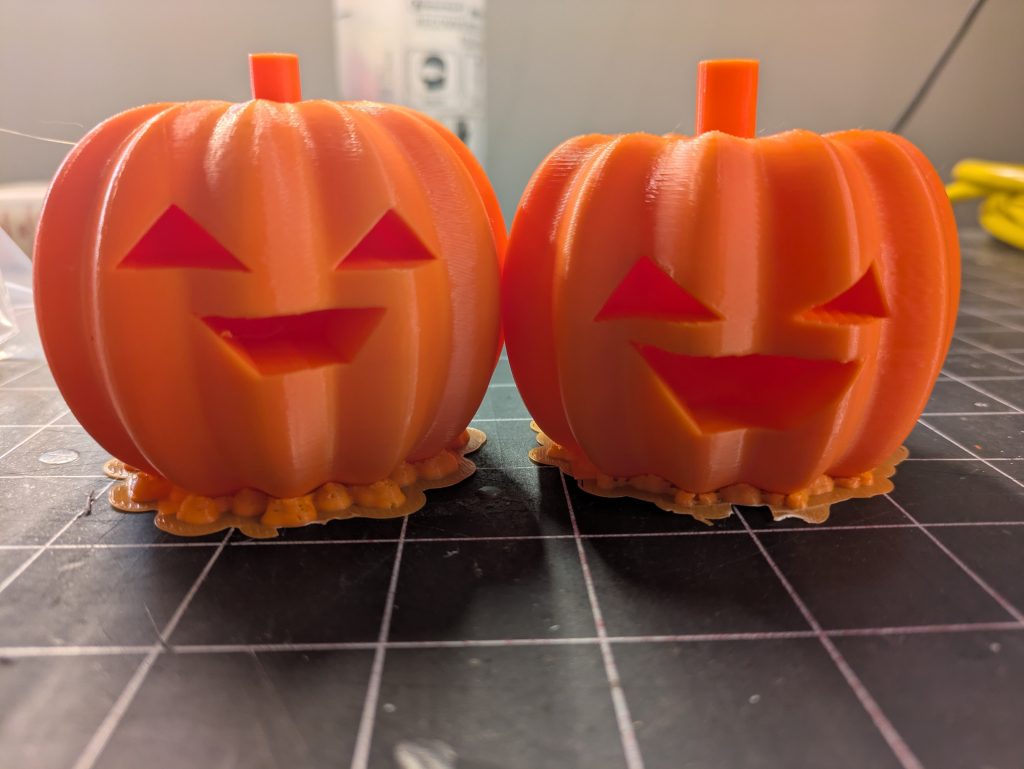 Two small plastic 3D printed pumpkins on a table