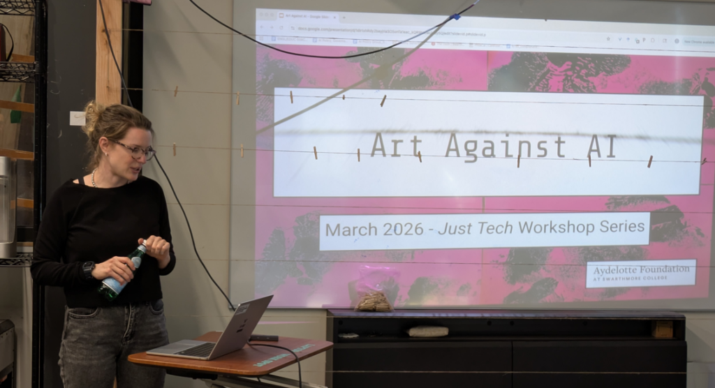 A lecturer presents a projection of a title slide for the workshop "Art Against AI"
