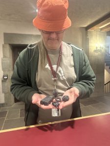 An image of Aaron Smith standing at the Clothier Hall welcome desk holding fidgets that he has printed